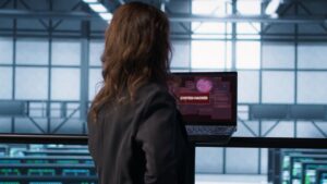 Un employé fait fait face à un ordinateur piraté, écran rouge.